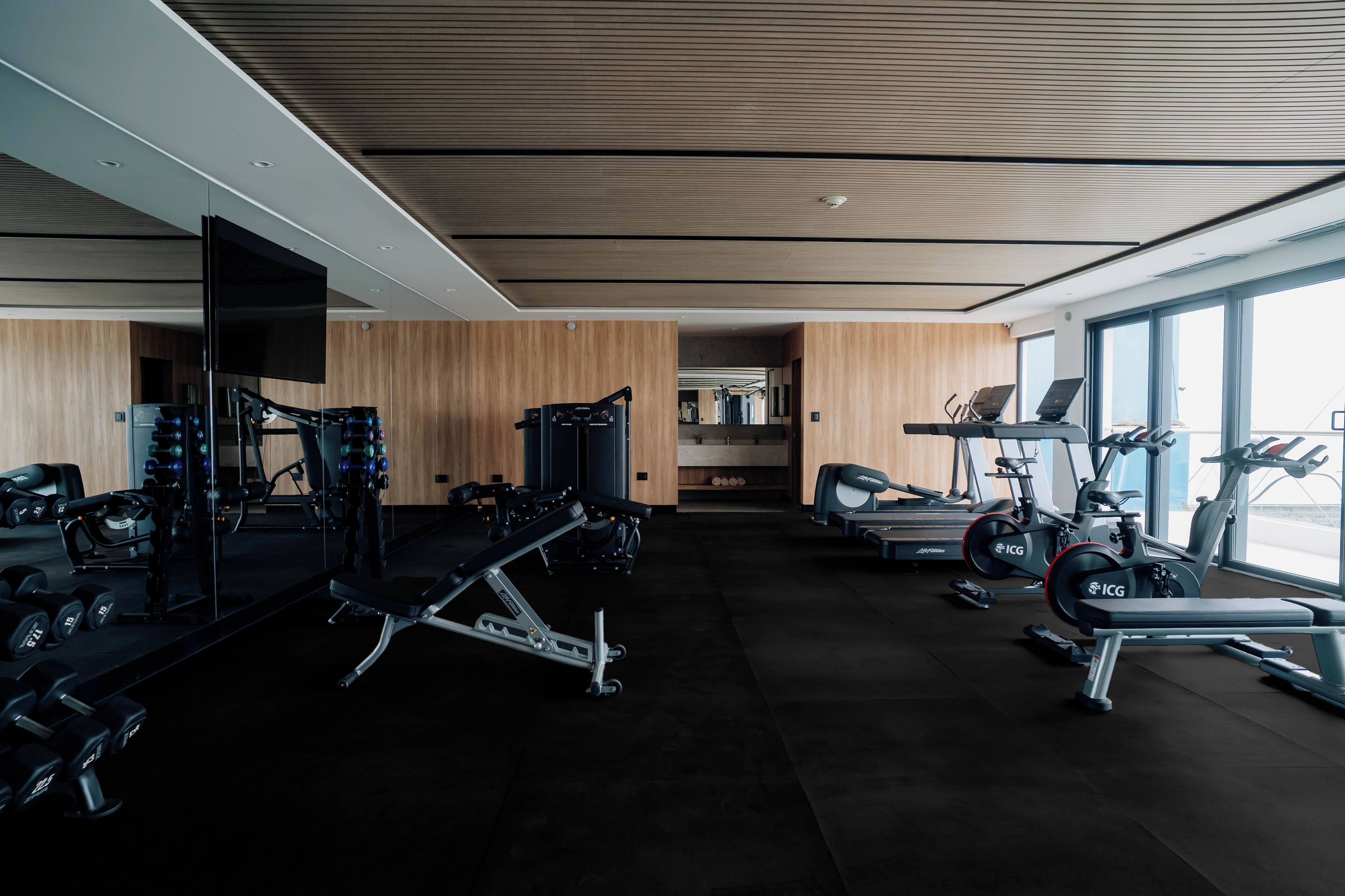 A modern gym with various exercise equipment, including treadmills, stationary bikes, and weight machines.