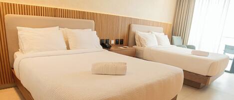 A hotel room with two beds, a wooden headboard, a nightstand, and a view of the outdoors.
