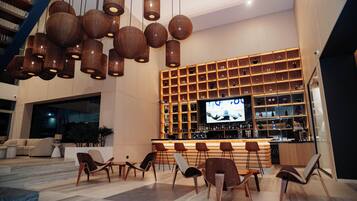 A modern lobby with a bar area, seating, and a large TV screen.
