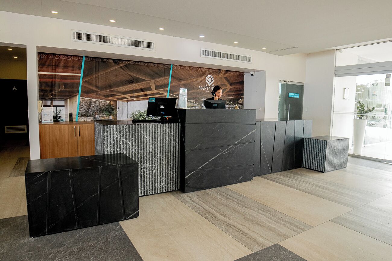 A reception area with a modern design, featuring a reception desk, a counter, and a seating area.