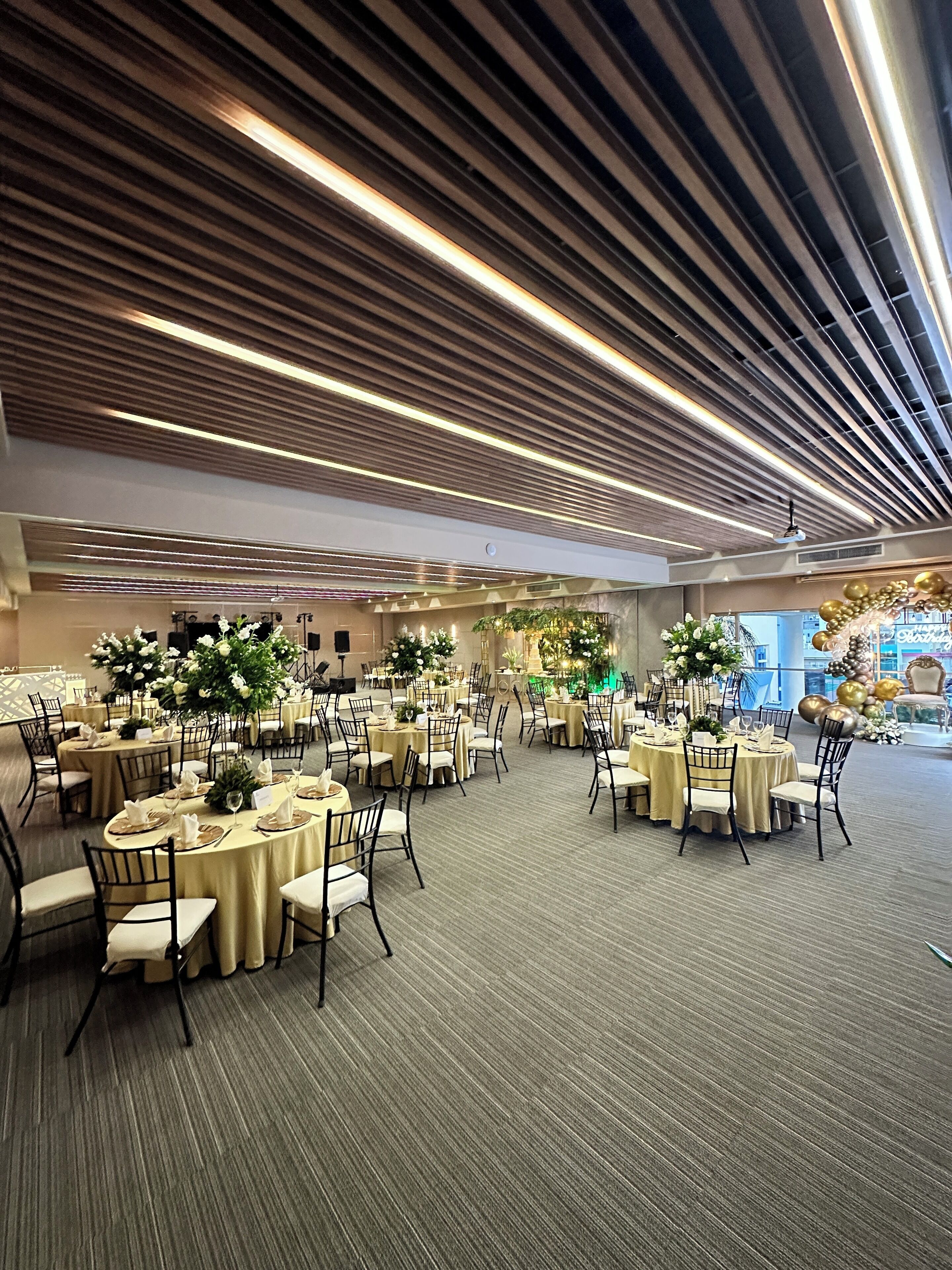 A spacious banquet hall with round tables, chairs, and floral centerpieces.