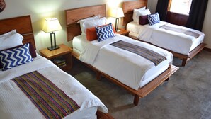 A hotel room with three single beds, each with a wooden headboard, white bedding, and colorful throw pillows. There are bedside tables with lamps, and the room has a tiled floor. - Soma Surf Resort (Tola)