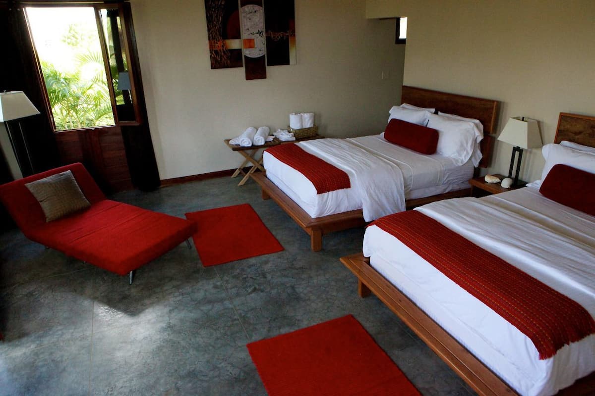 Une chambre d’hôtel avec deux lits, des meubles rouges et une petite table avec des serviettes.
