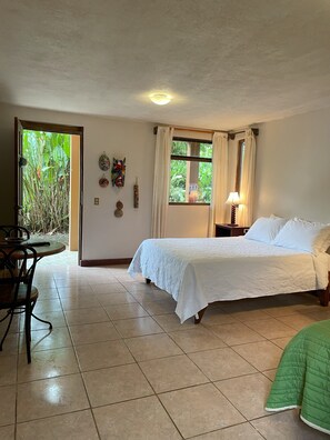 A room with a bed, a desk, and a window with curtains.