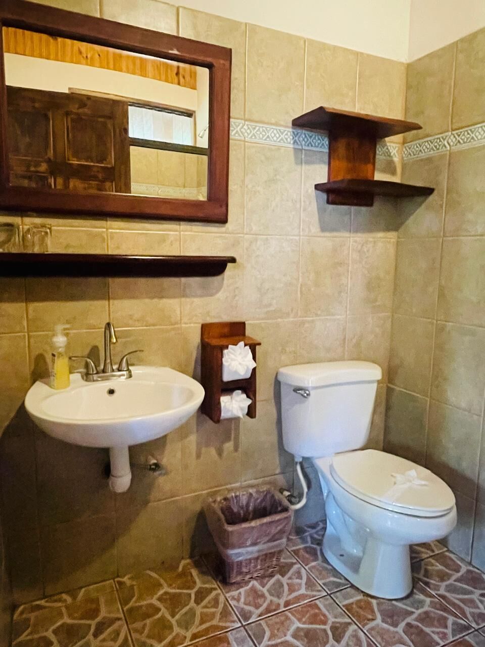 A bathroom with a sink, toilet, and a trash bin.