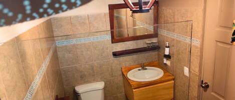 A bathroom with a toilet, sink, mirror, and decorative tiles.