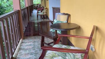 A covered outdoor seating area with wooden furniture and a tiled floor.
