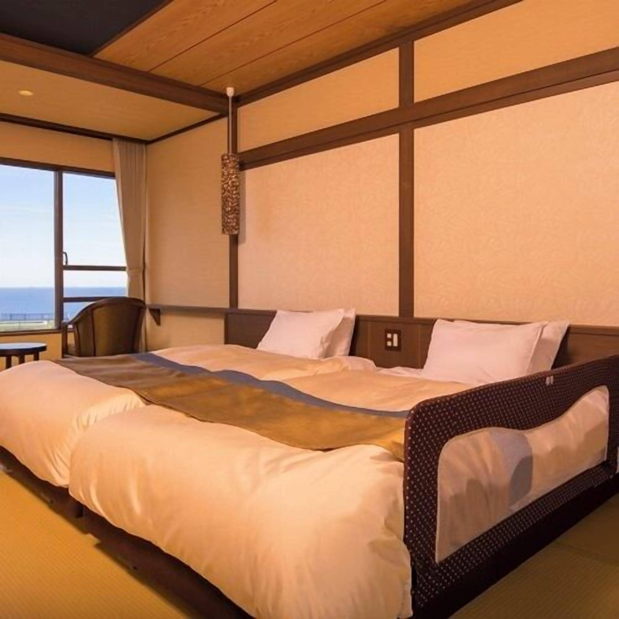 A hotel room with a large bed, a view of the sea, and a wooden ceiling.