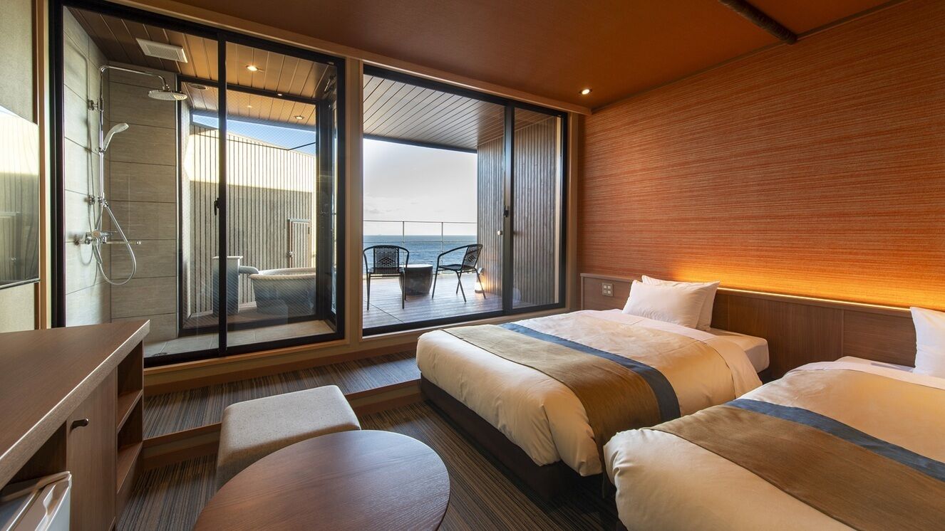 A modern hotel room with a balcony, a shower, a bed, a desk, and a chair.