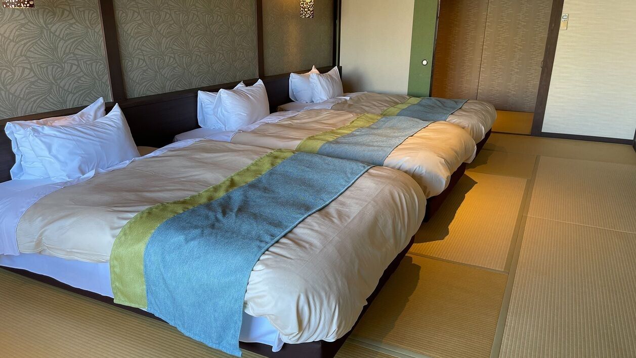 Una habitación de hotel con una cama grande, cabecera, pared con diseño decorativo y puerta corrediza.
