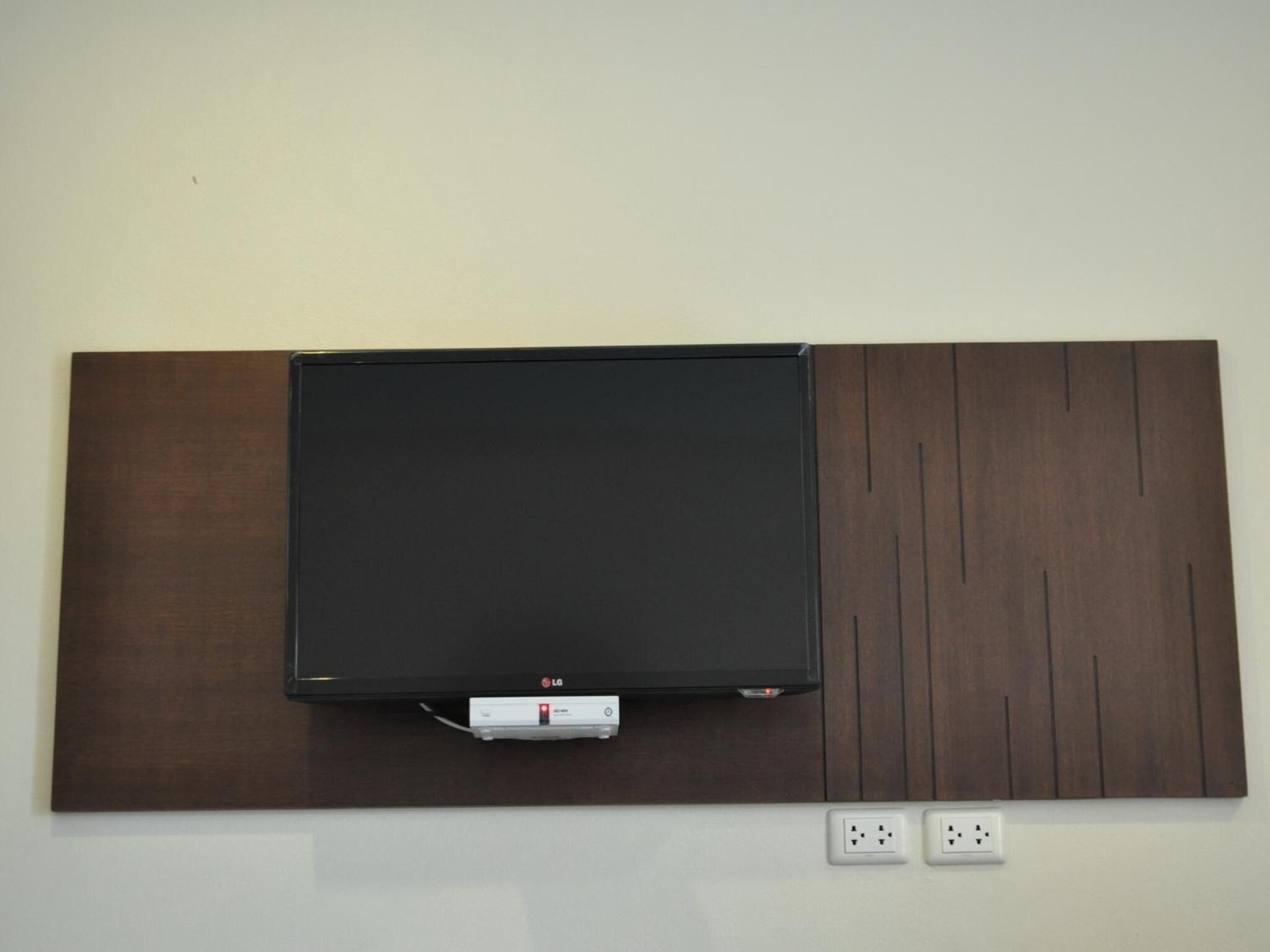 A flat-screen TV mounted on a wall with a wooden panel design.