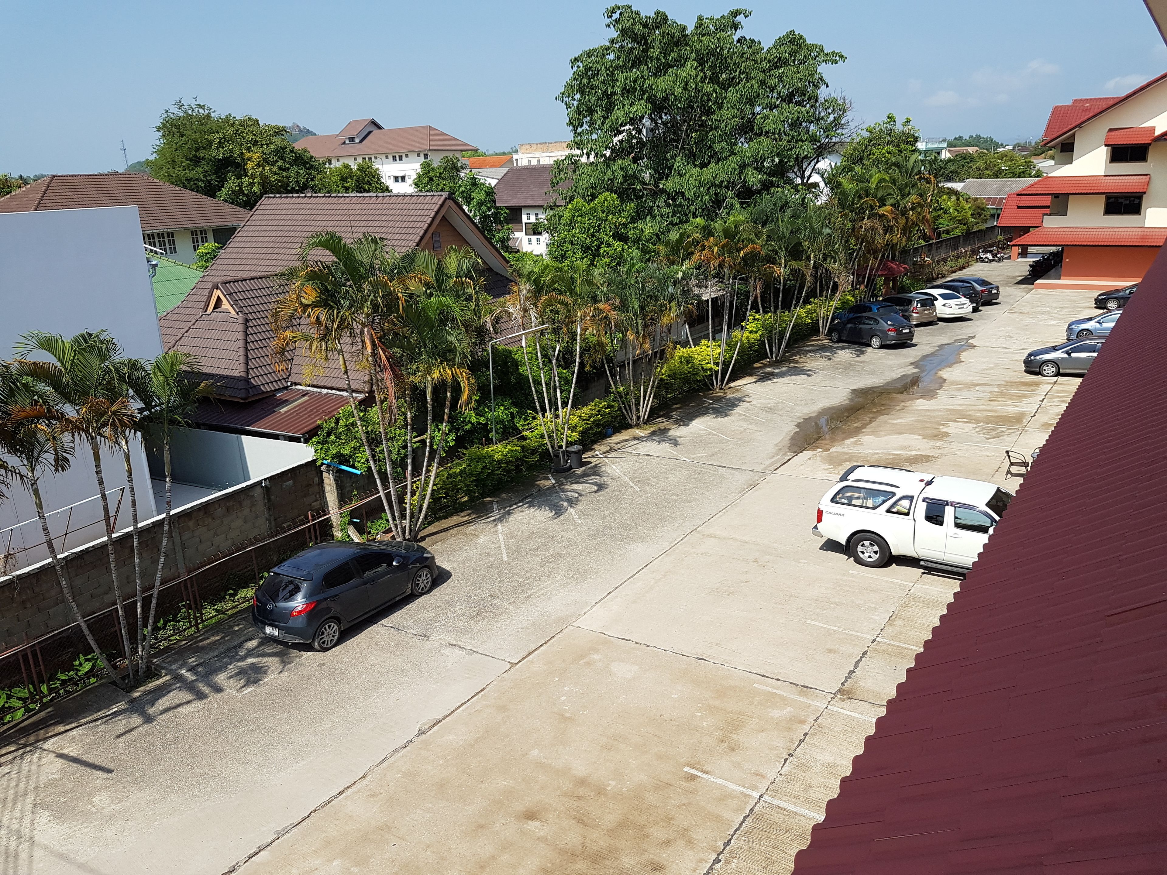 A residential street with parked cars and houses.