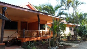 A two-story house with a wooden balcony, surrounded by tropical vegetation. - Khunnam Rimtarn Resort (Mae Sai)