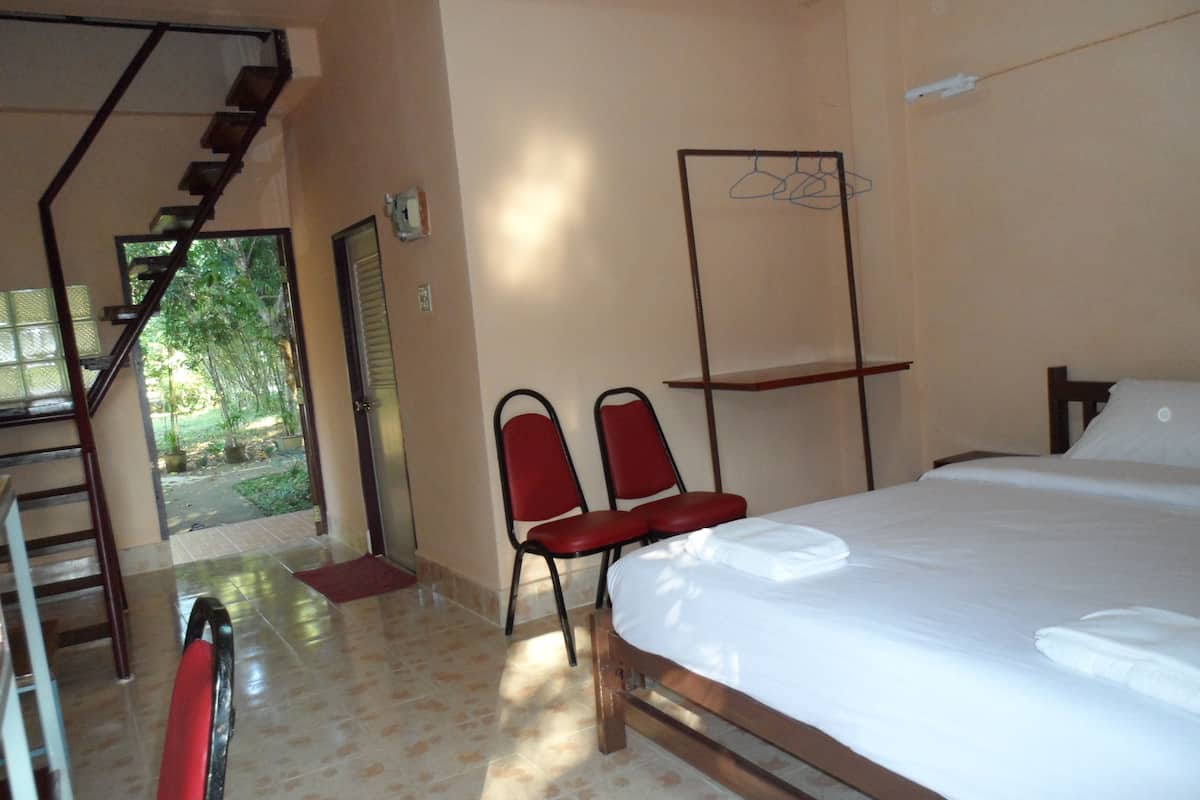 Une chambre à coucher comprenant un lit, une chaise, une petite table, un luminaire suspendu et un escalier menant à un balcon.