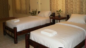 A hotel room with two single beds, a wooden headboard, a small table, and a potted plant. - Khunnam Rimtarn Resort (Mae Sai)