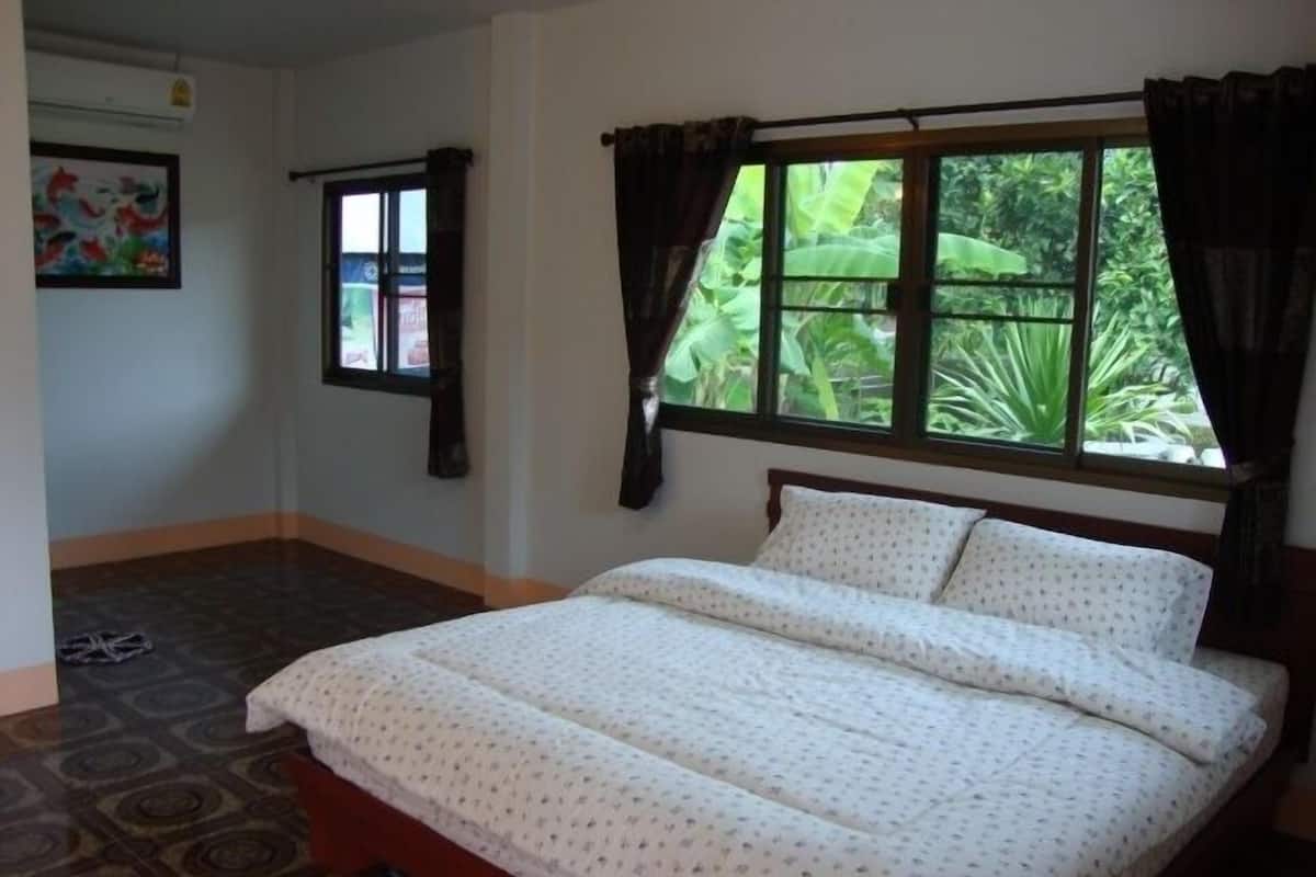 Une chambre à coucher avec un lit, une fenêtre avec des rideaux, une porte et un sol à motifs.