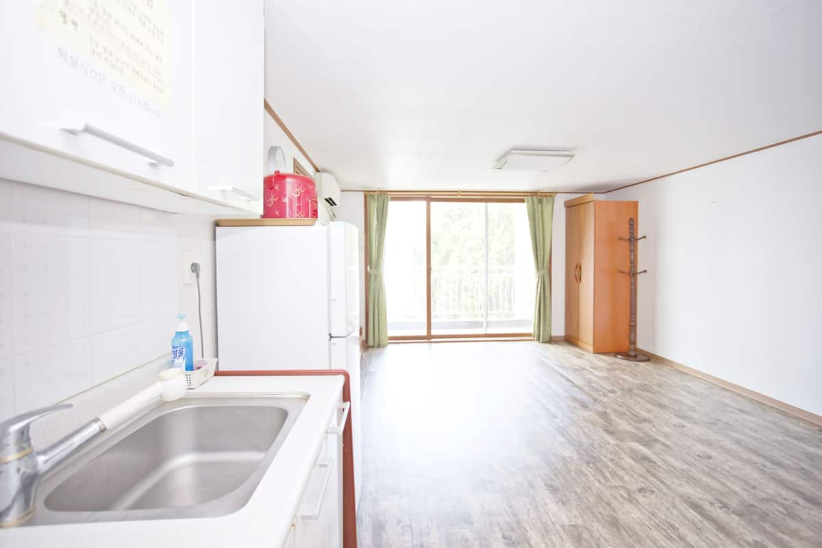 A kitchen with a sink, a refrigerator, and a window with curtains.