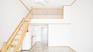 Eine geräumige, zweistöckige Wohnung mit einer Holztreppe, einer Küchenzeile und heller Einrichtung.