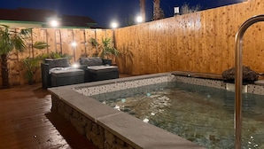A hot tub area with stone steps, wooden walls, and outdoor seating. - Morning Beach Pension (Jeju City)