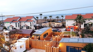 A coastal hotel with multiple buildings, including a main house with a red roof and several smaller structures with string lights. - Morning Beach Pension (Jeju City)