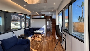 A modern interior with a sofa, a small table, and a staircase leading to an upper level. - Morning Beach Pension (Jeju City)