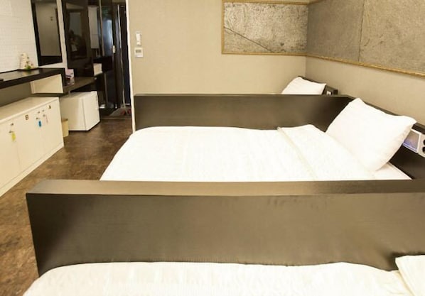 A hotel room with two beds, a kitchenette, and a large abstract painting on the wall.