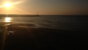 A beach with a pier and a lighthouse in the distance. - Hotel Major 2 (Jeju City)