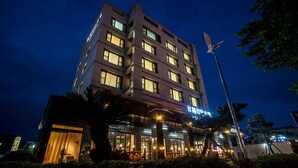 Un hotel de varios pisos con ventanas iluminadas y un restaurante visible en la planta baja.