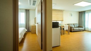 Una habitación de hotel con cama, escritorio con computadora, sofá y ventana con cortinas.