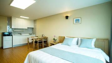 Una habitación de hotel con cama, escritorio y kitchenette.