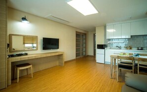 A modern kitchen with white cabinets, a built-in oven, and a dining area with wooden furniture. - Haerian Hotel (Seogwipo)