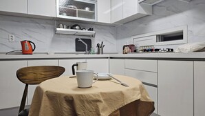 Une cuisine moderne avec des meubles blancs, un pare-feu en marbre et un coin repas avec une table dressée pour deux personnes.