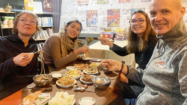 Un groupe de personnes est réuni autour d’une table dans un restaurant, où l’on peut voir différents plats.