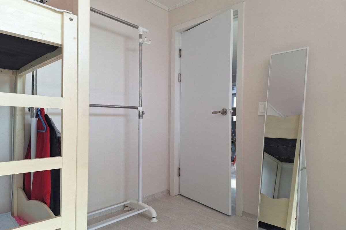 Ein Zimmer mit Holzschrank, Metalldörr und einem großen Spiegel.