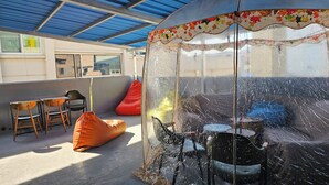 Un espace extérieur abrité avec des chaises, une table et un pouf rouge.