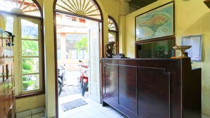 A reception area with a wooden cabinet, a map on the wall, and a motorcycle outside. - Bali Duta Wisata Beach Inn (Kuta)
