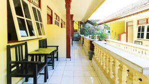 A corridor with a tiled floor, wooden benches, a railing with balusters, and a staircase in the background. - Bali Duta Wisata Beach Inn (Kuta)