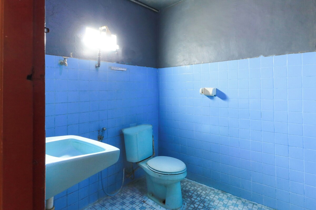 Un baño con paredes de azulejos azules, un lavamanos blanco y un inodoro.