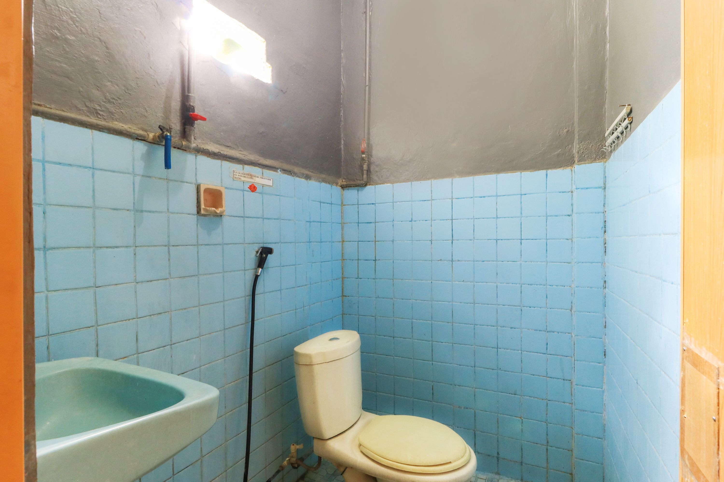 Un baño pequeño con azulejos azules, un inodoro blanco y un lavabo verde.