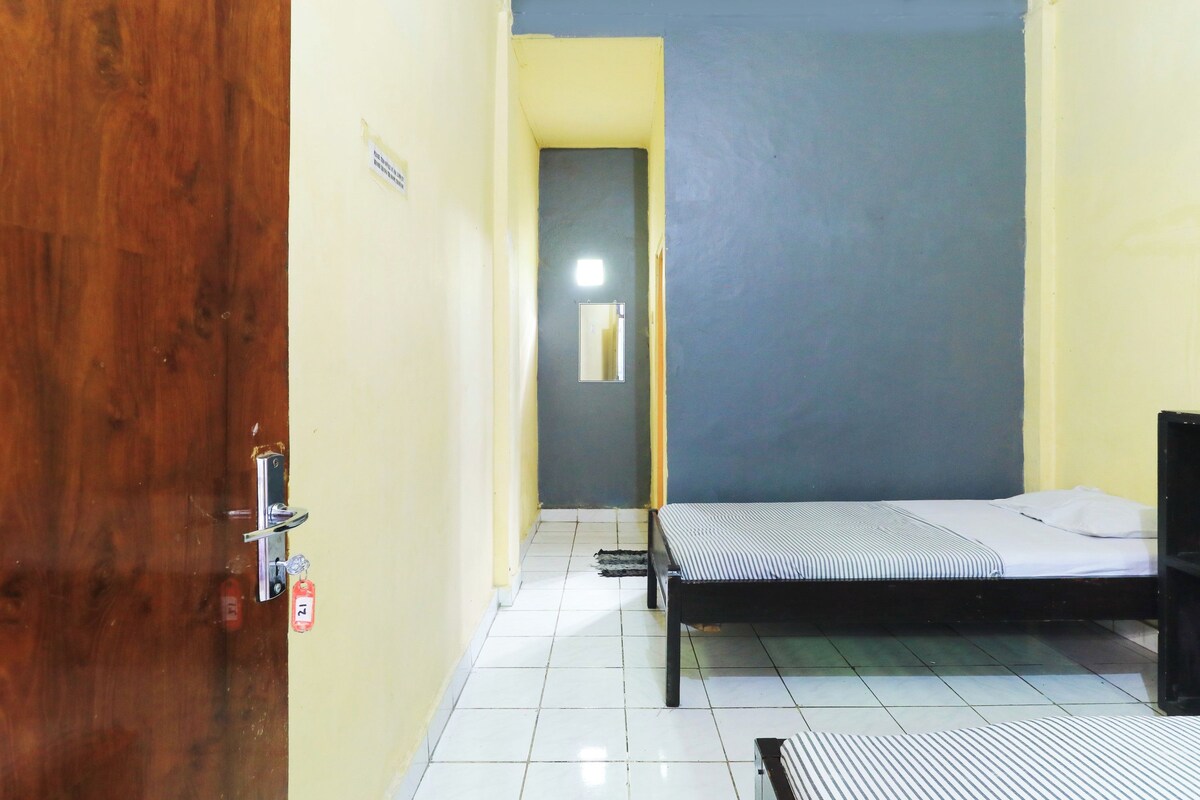 Una stanza con un letto, una porta in legno e un pavimento piastrellato.