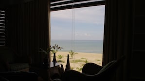 Una stanza con vista sulla spiaggia, una sedia e un tavolino con una pianta.