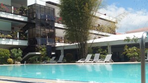 Un hotel con piscina, diversi balconi fioriti e un cielo azzurro limpido.