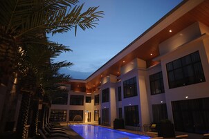 Un hotel moderno con una amplia piscina interior, varios pisos y grandes ventanales.