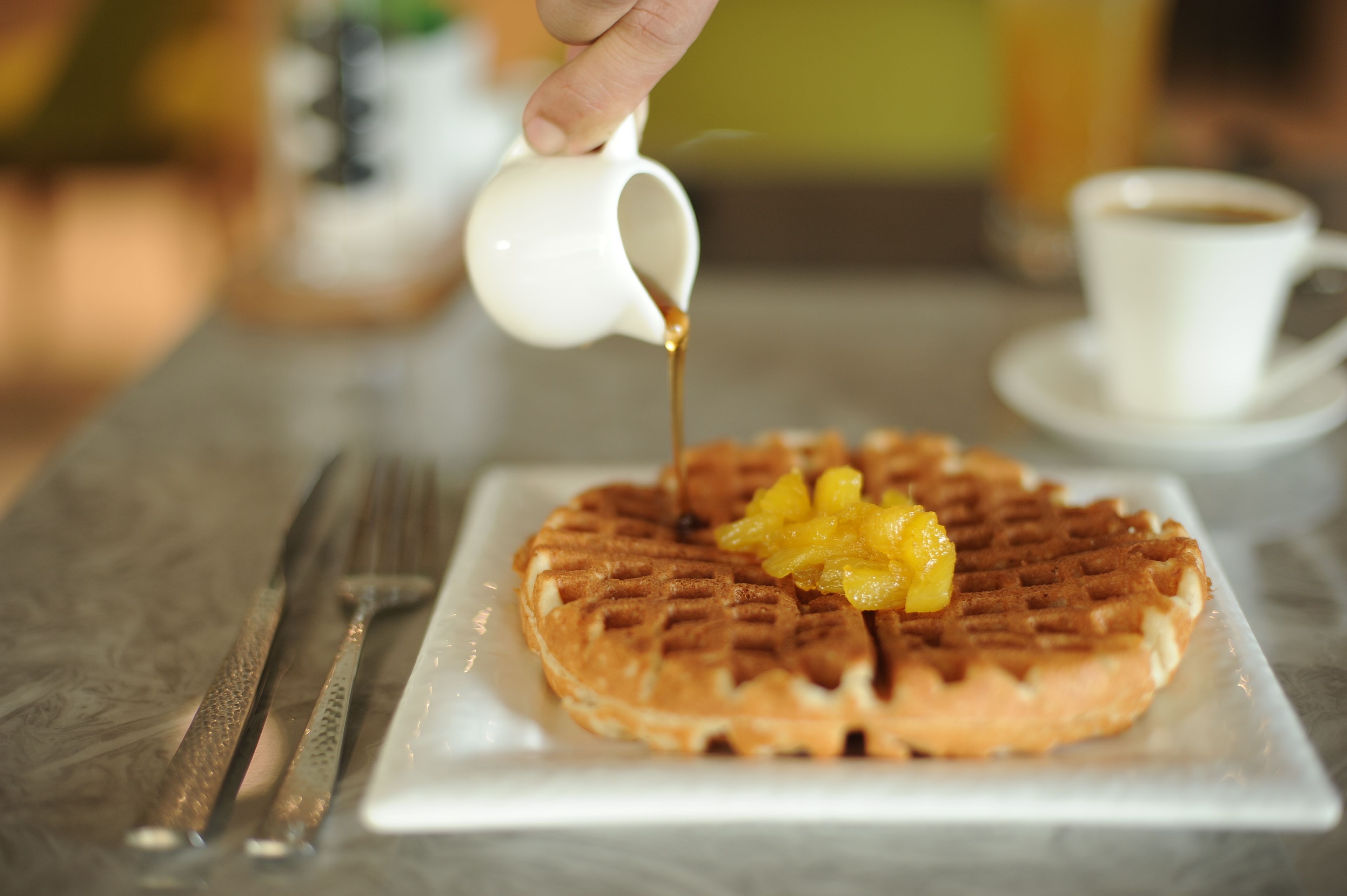 Une gaufre arrosée de sirop, posée sur une assiette blanche.