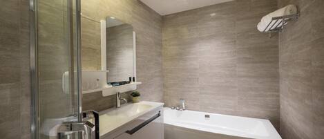 Un baño moderno con cabina de ducha de vidrio, un lavabo blanco y una bañera independiente.