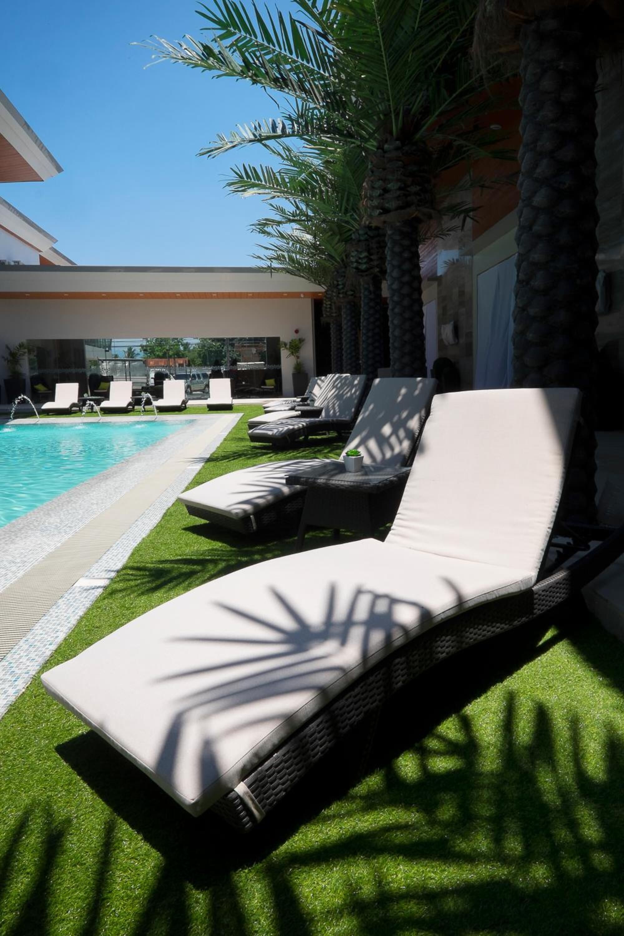 A poolside area with lounge chairs and palm trees.