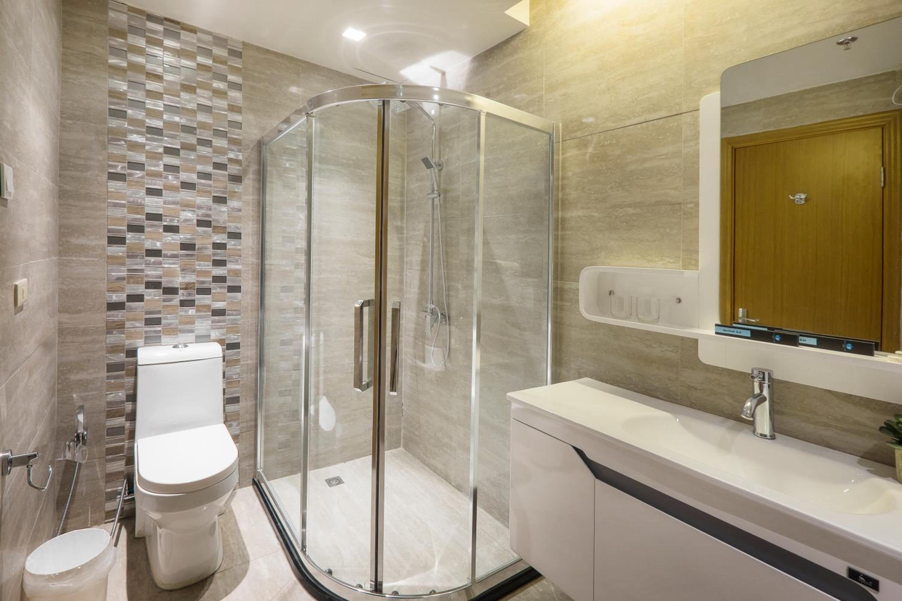 A modern bathroom with a glass shower enclosure, a toilet, a sink, and a mirror.