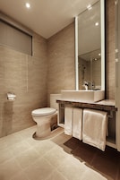 A modern bathroom with a toilet, sink, and large mirror.