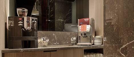 A modern kitchen with a built-in coffee machine, wooden cabinets, and marble countertops.