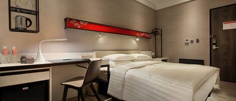 A hotel room with a bed, desk, chair, and a minibar.